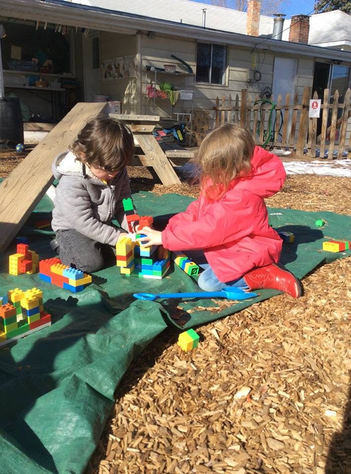 Two children playing with colorful building blocks outdoors