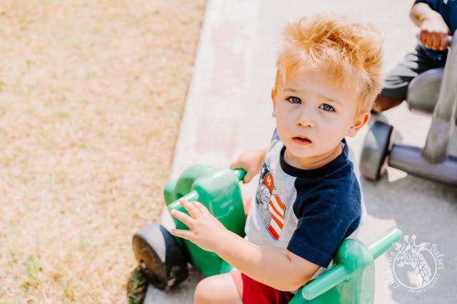 Child sitting on a green toy