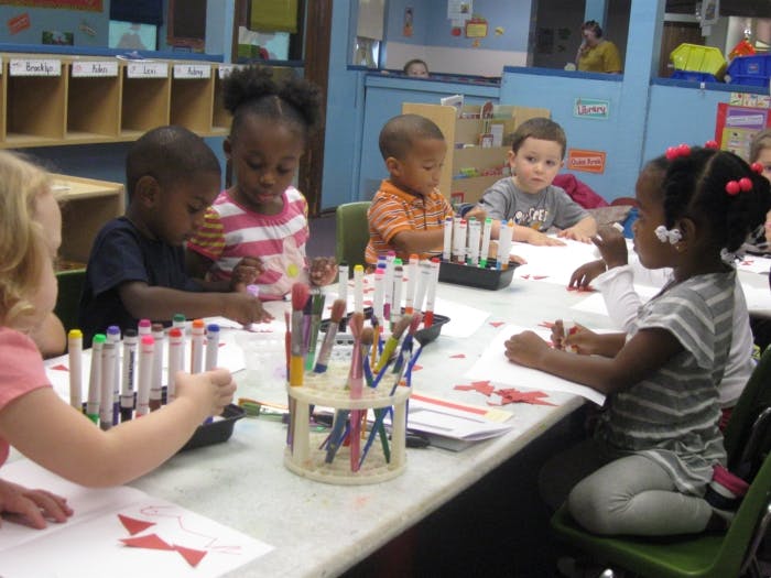 Children sitting at a table with markers and paper