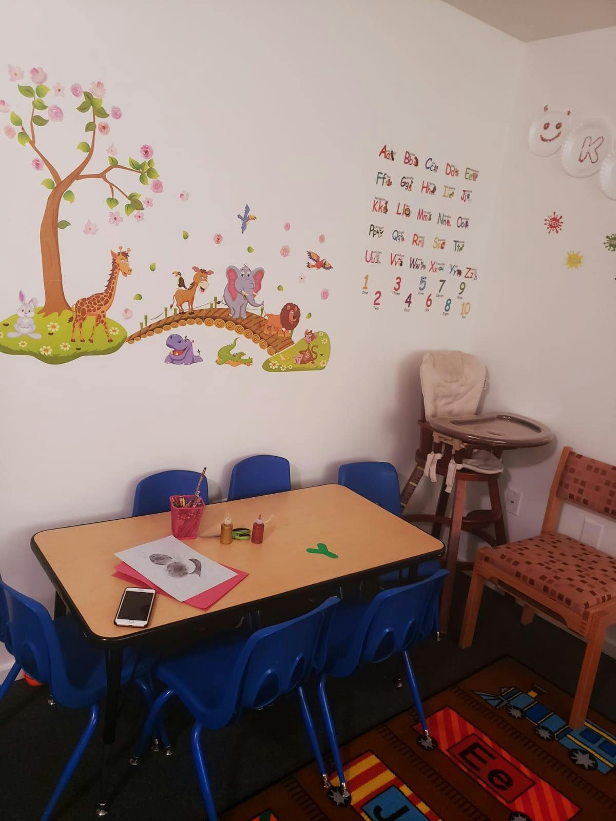 Classroom with small table and chairs, wall decals of animals, alphabet, and numbers