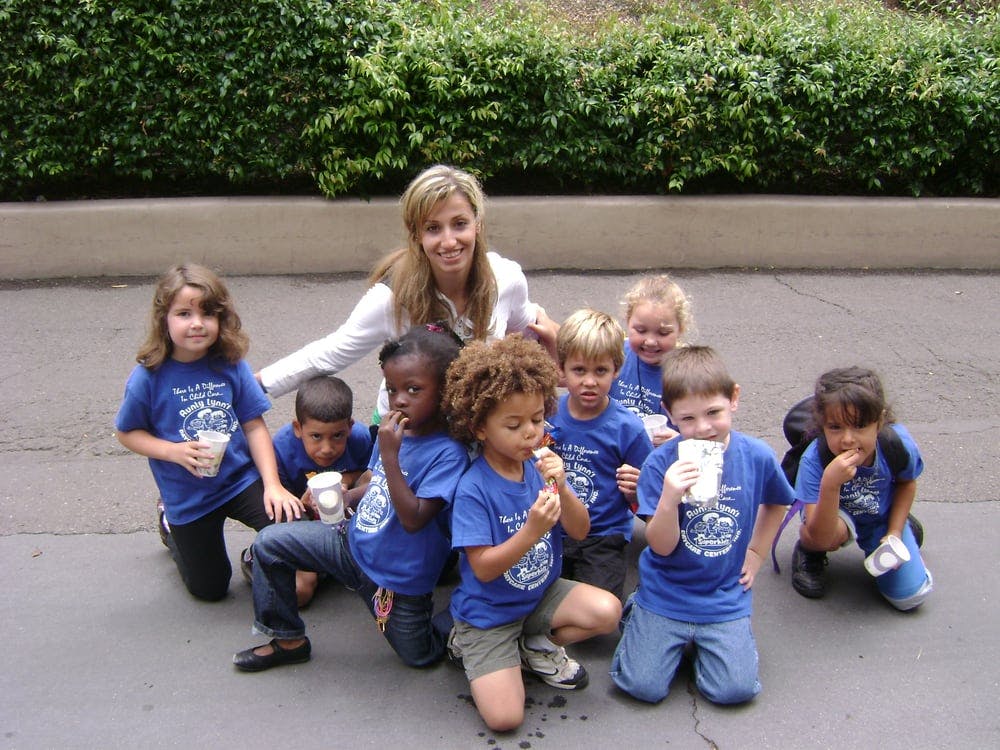 Adult and multiple children in blue shirts holding cups and snacks