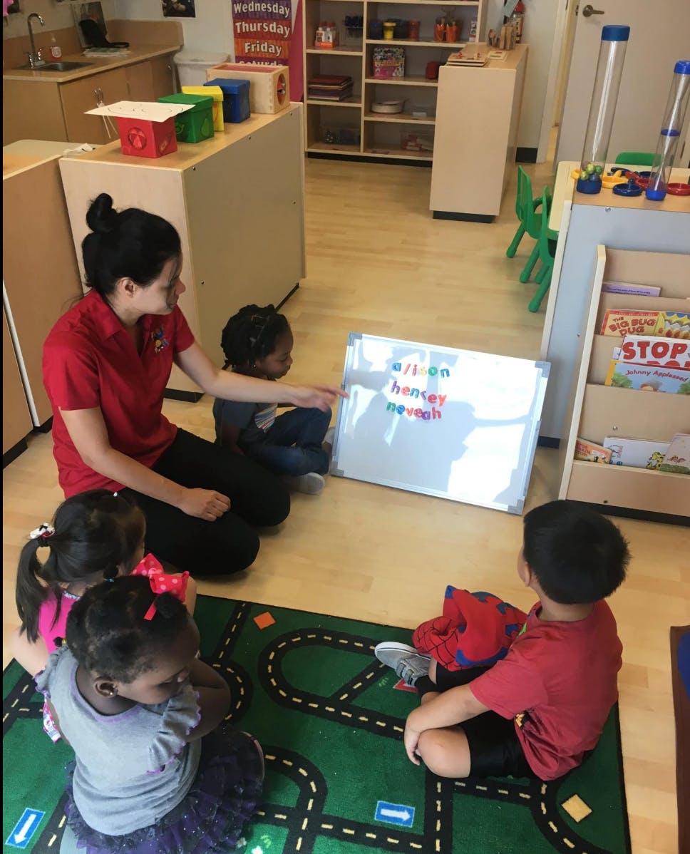 Person and children sitting on floor looking at a whiteboard