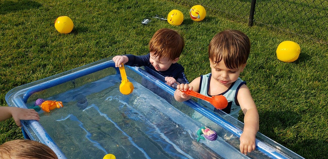 Two children playing with toys in a small inflatable pool