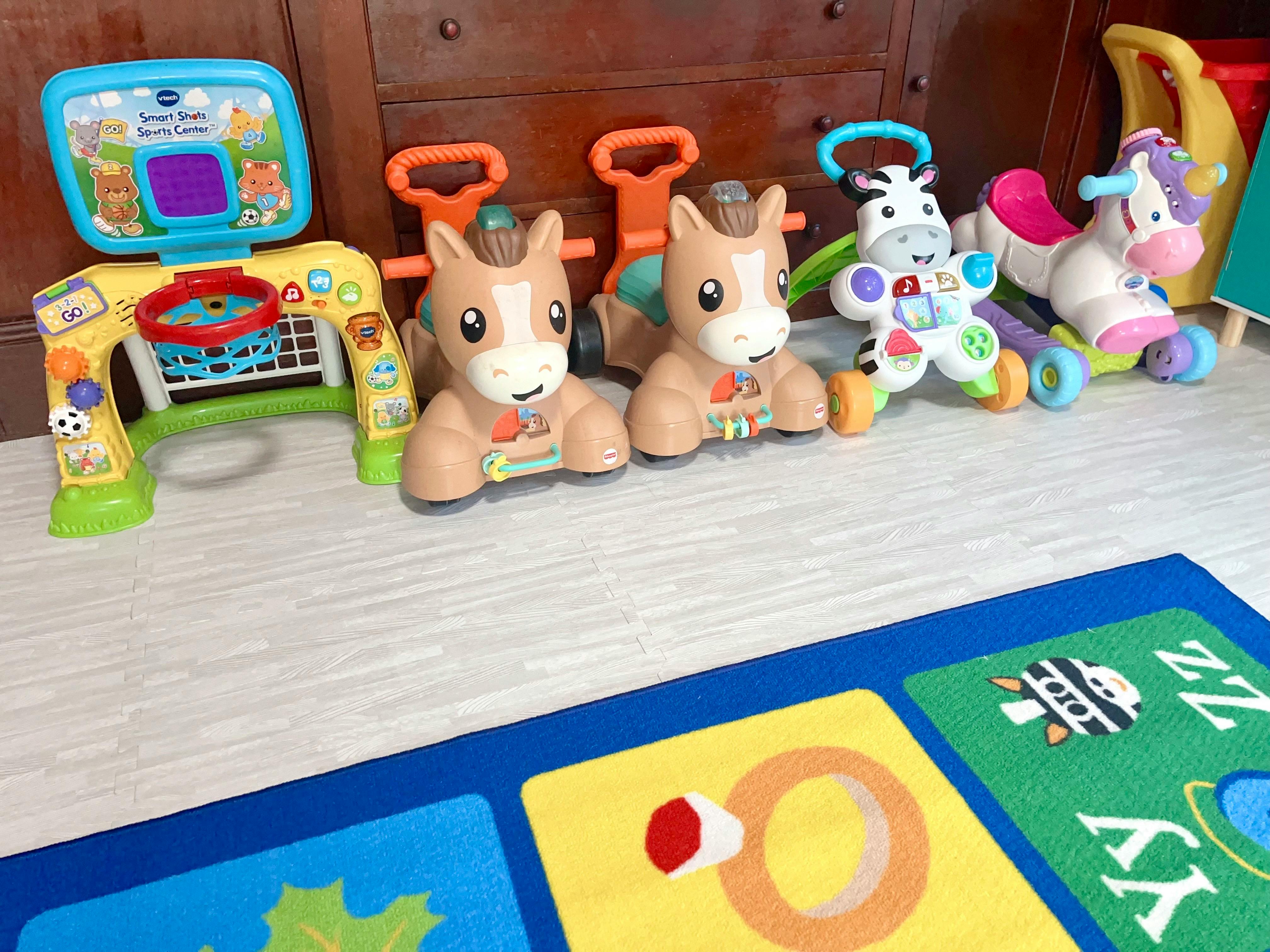 Children's toys including a play table, two horse toys, and two ride-on toys