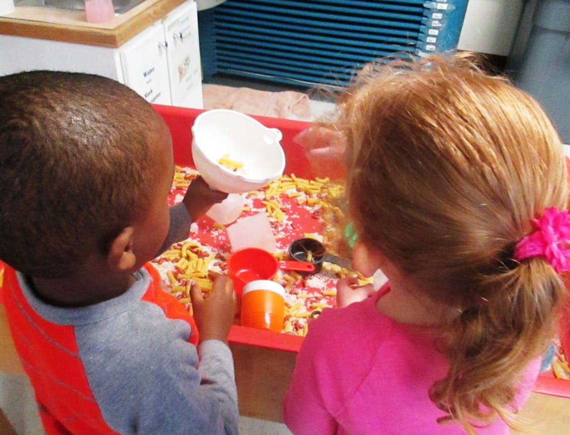 Two children playing with sensory bin materials