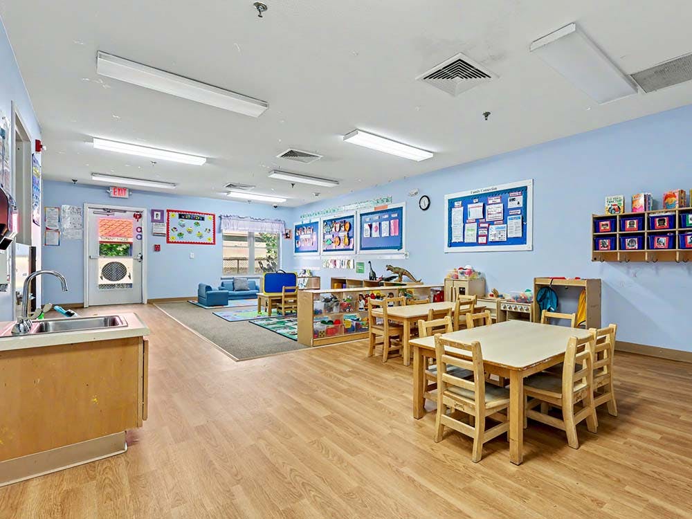 Children's classroom with small wooden tables and chairs, and play areas