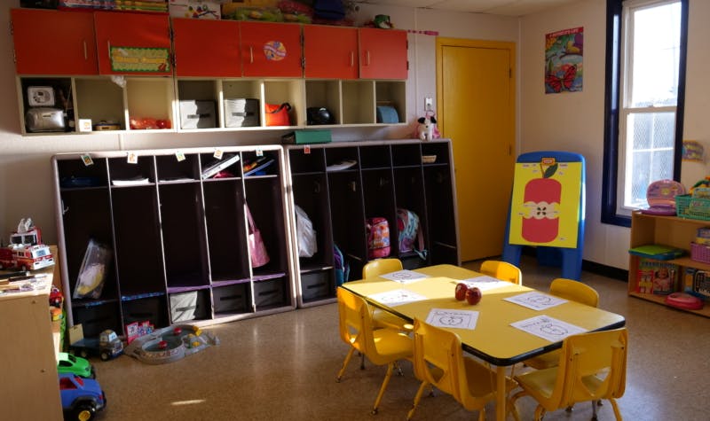 Classroom with cubbies, yellow tables, and chairs