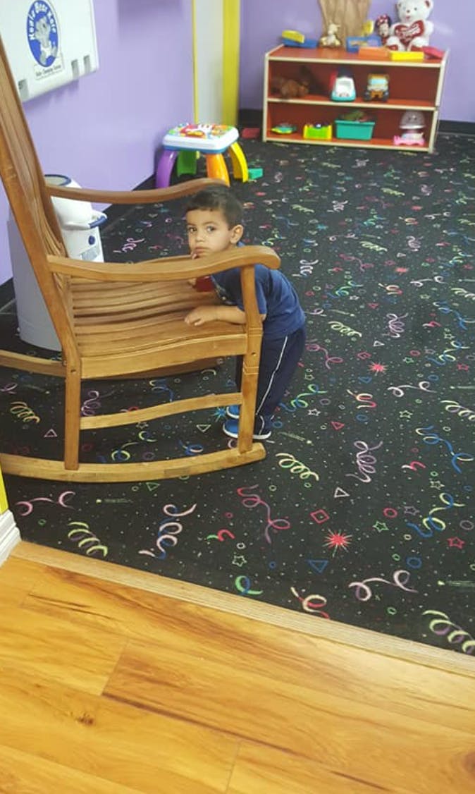 Child peeking from behind a wooden rocking chair
