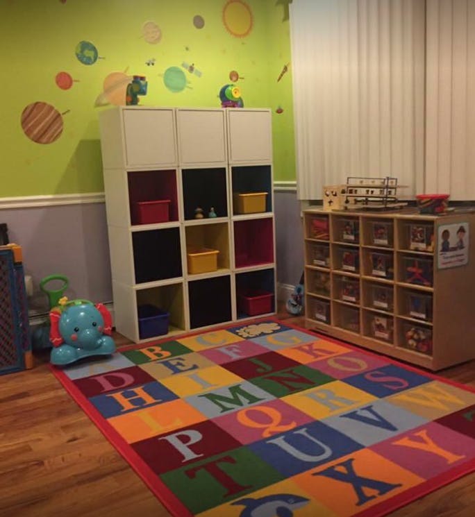 Playroom with alphabet rug, storage shelves, and toys