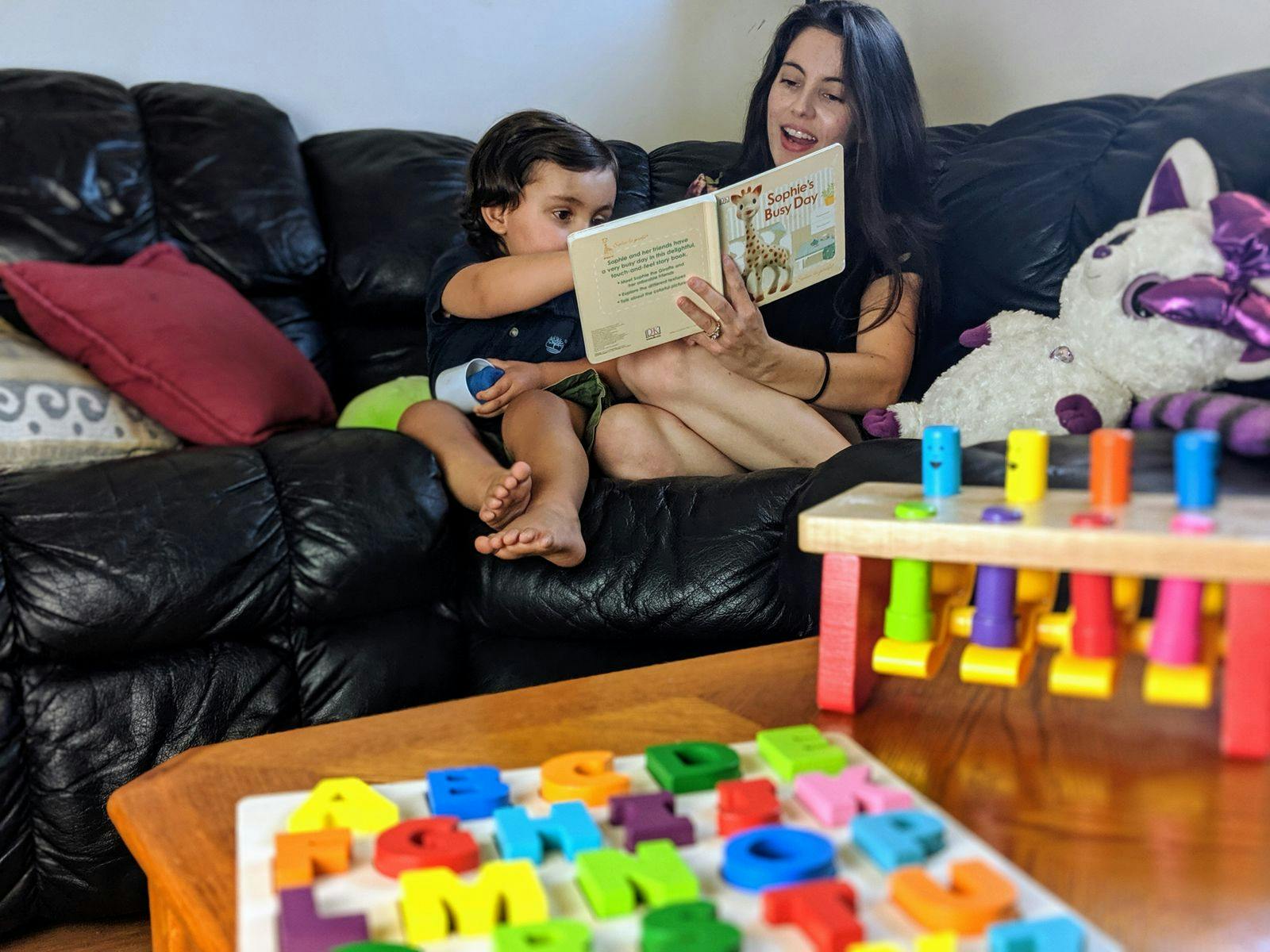 Person and child sitting on a couch reading a book
