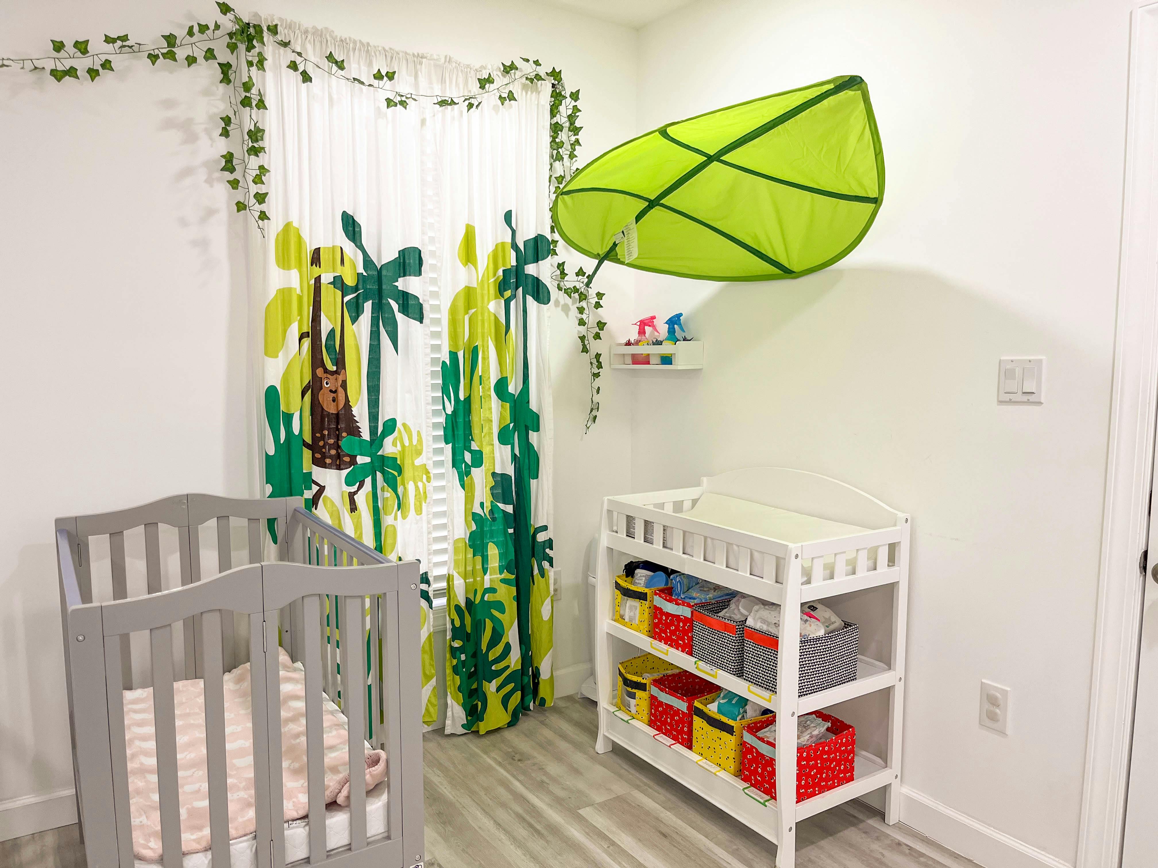 Nursery room with a crib, changing table, and leaf-patterned curtains