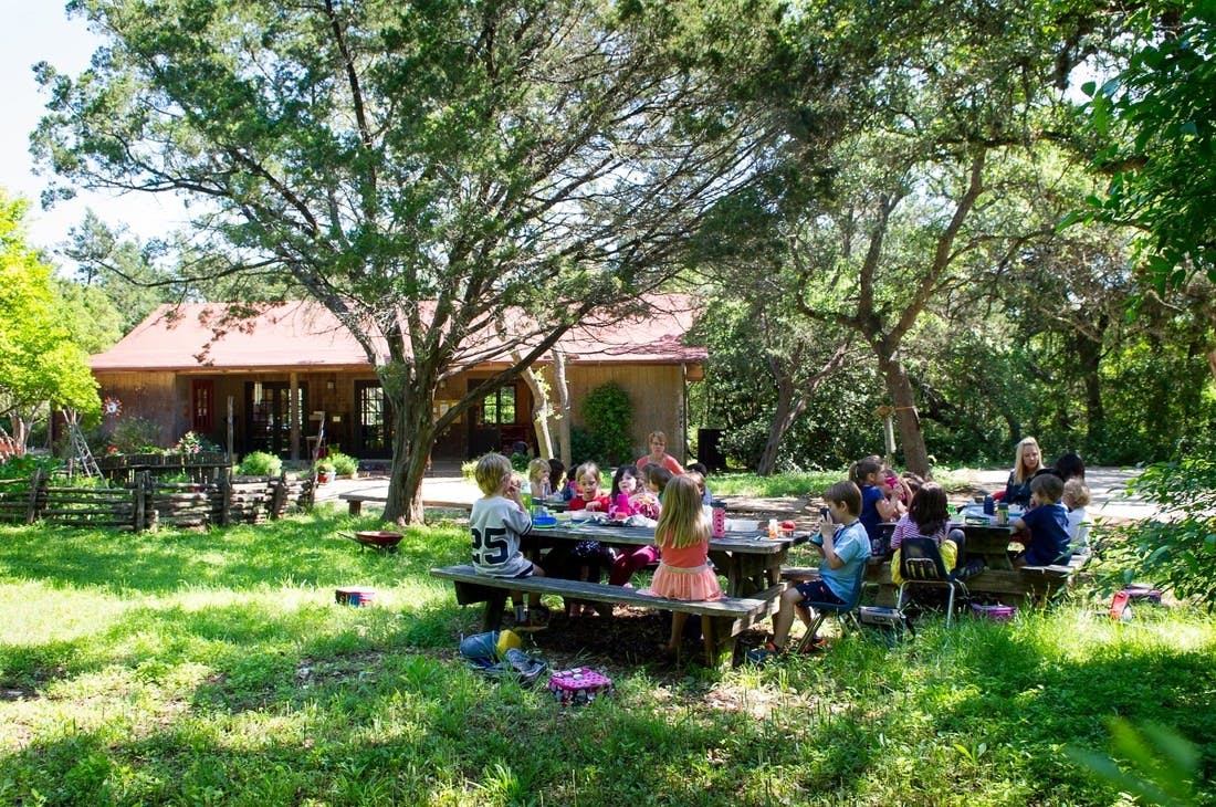 Children sitting at picnic tables outdoors