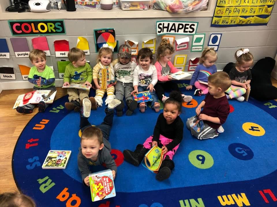 Children sitting on a rug with books