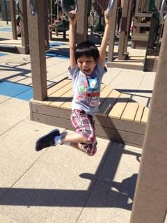 Child hanging from monkey bars