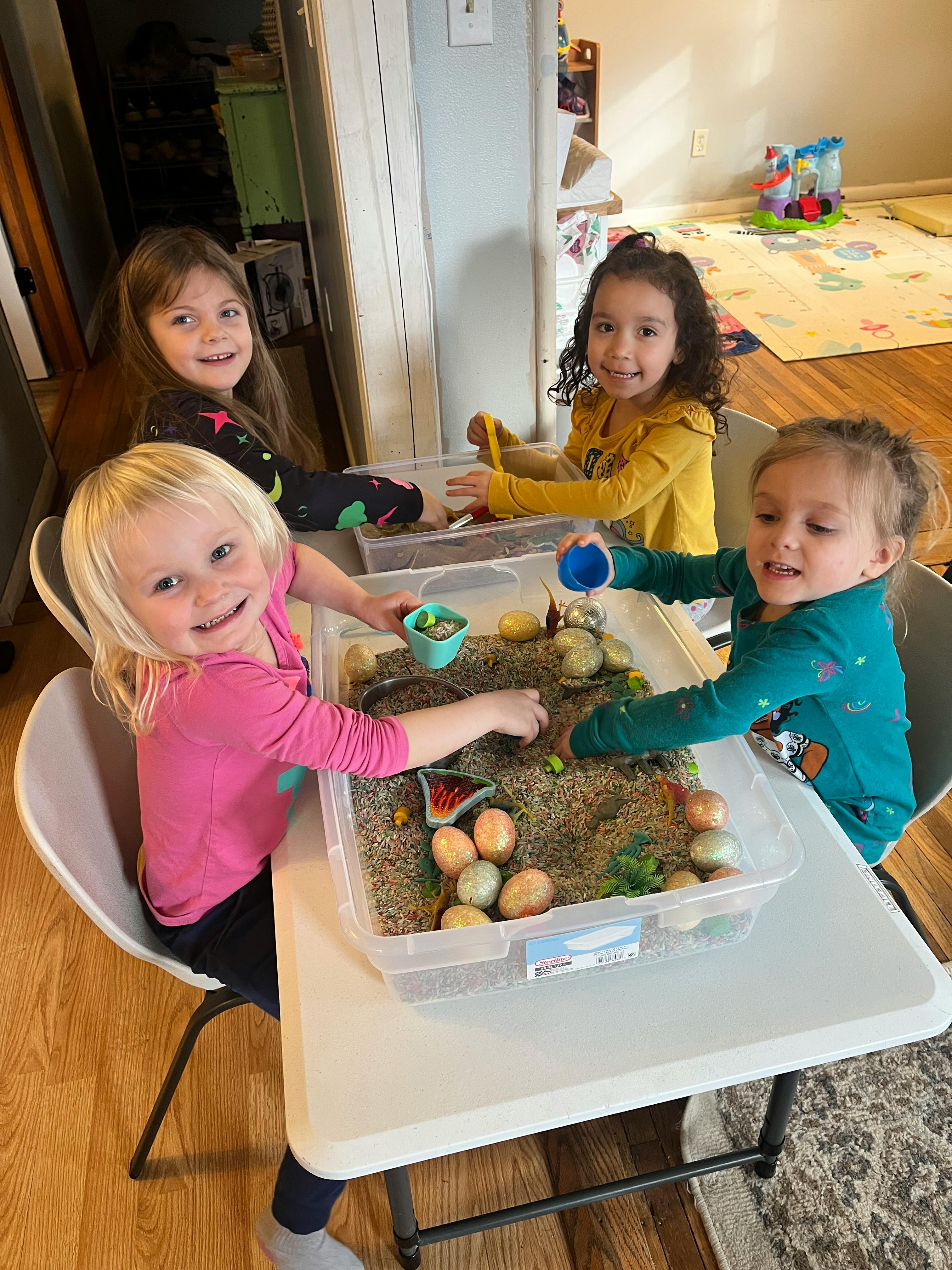 Four children playing with a sensory bin at a table