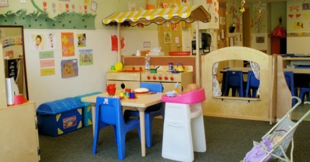 Playroom with small table and chairs, toy kitchen, and puppet theater