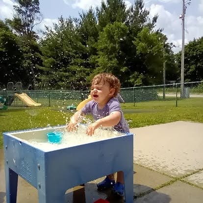 Child splashing water in a table on a playground