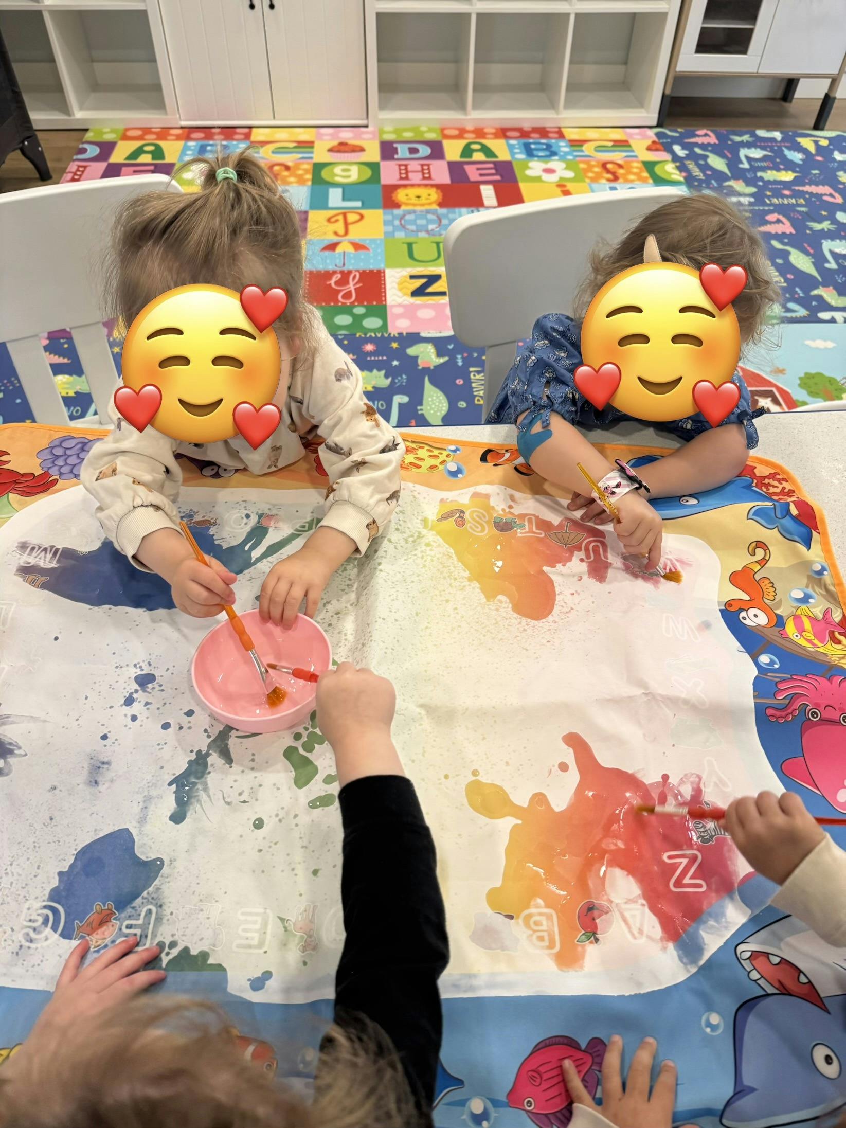 children painting with water on a mat in a classroom