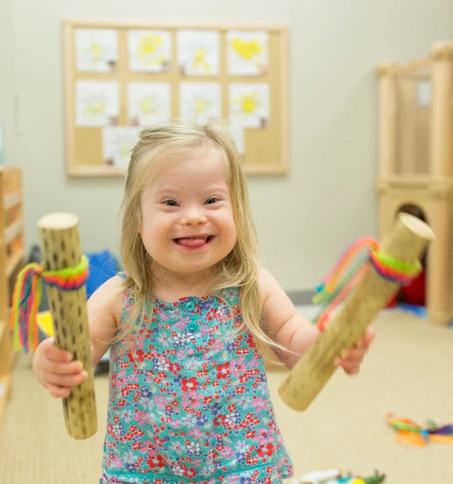 Child holding two wooden instruments