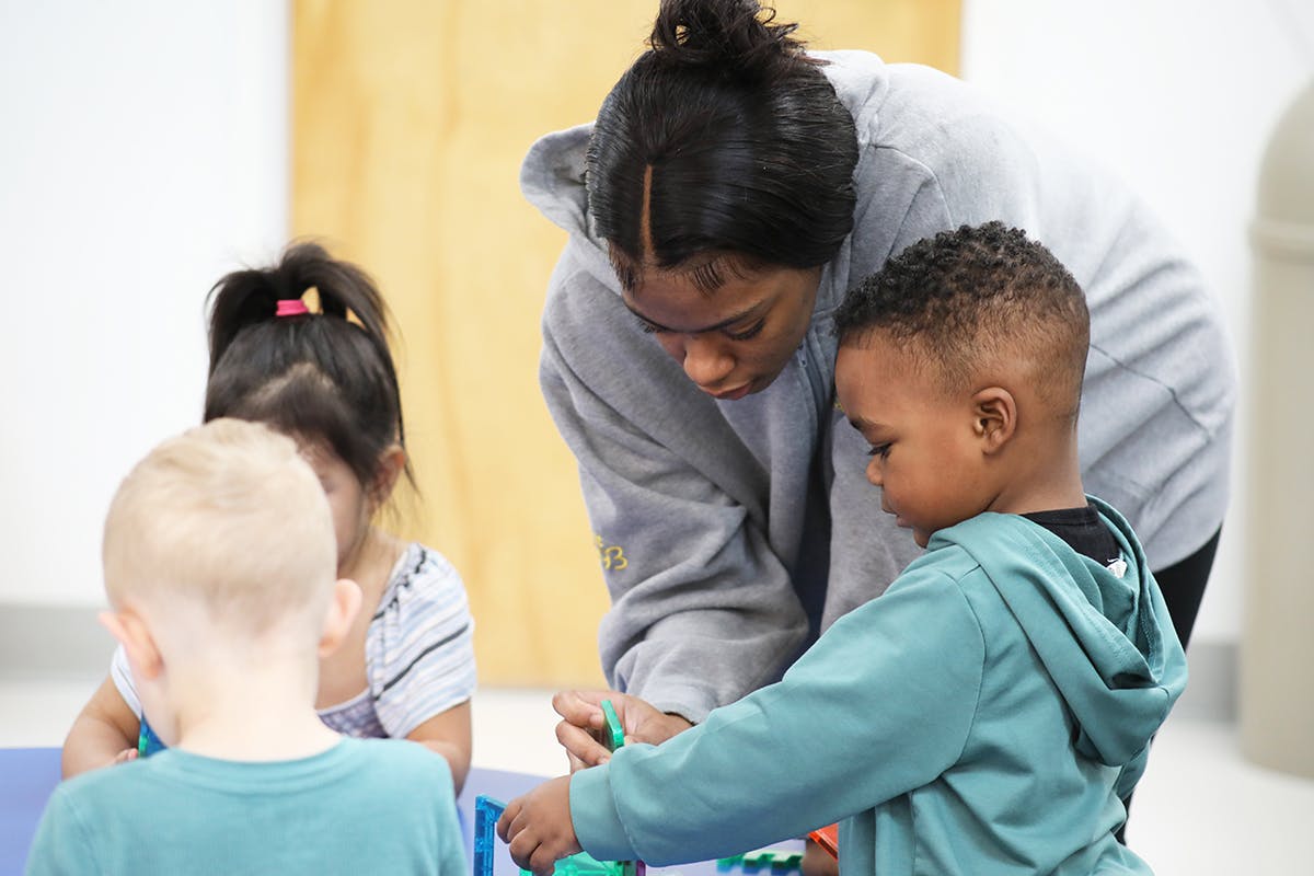 Adult and three children playing with blocks