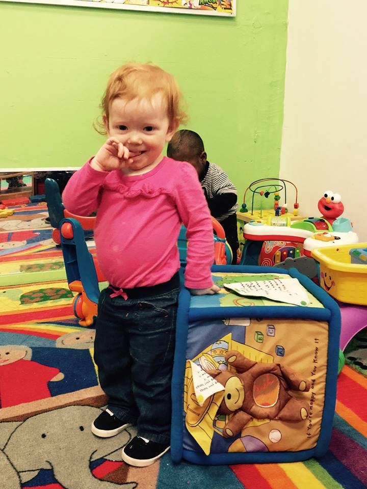 Child in a pink shirt standing next to a soft play cube