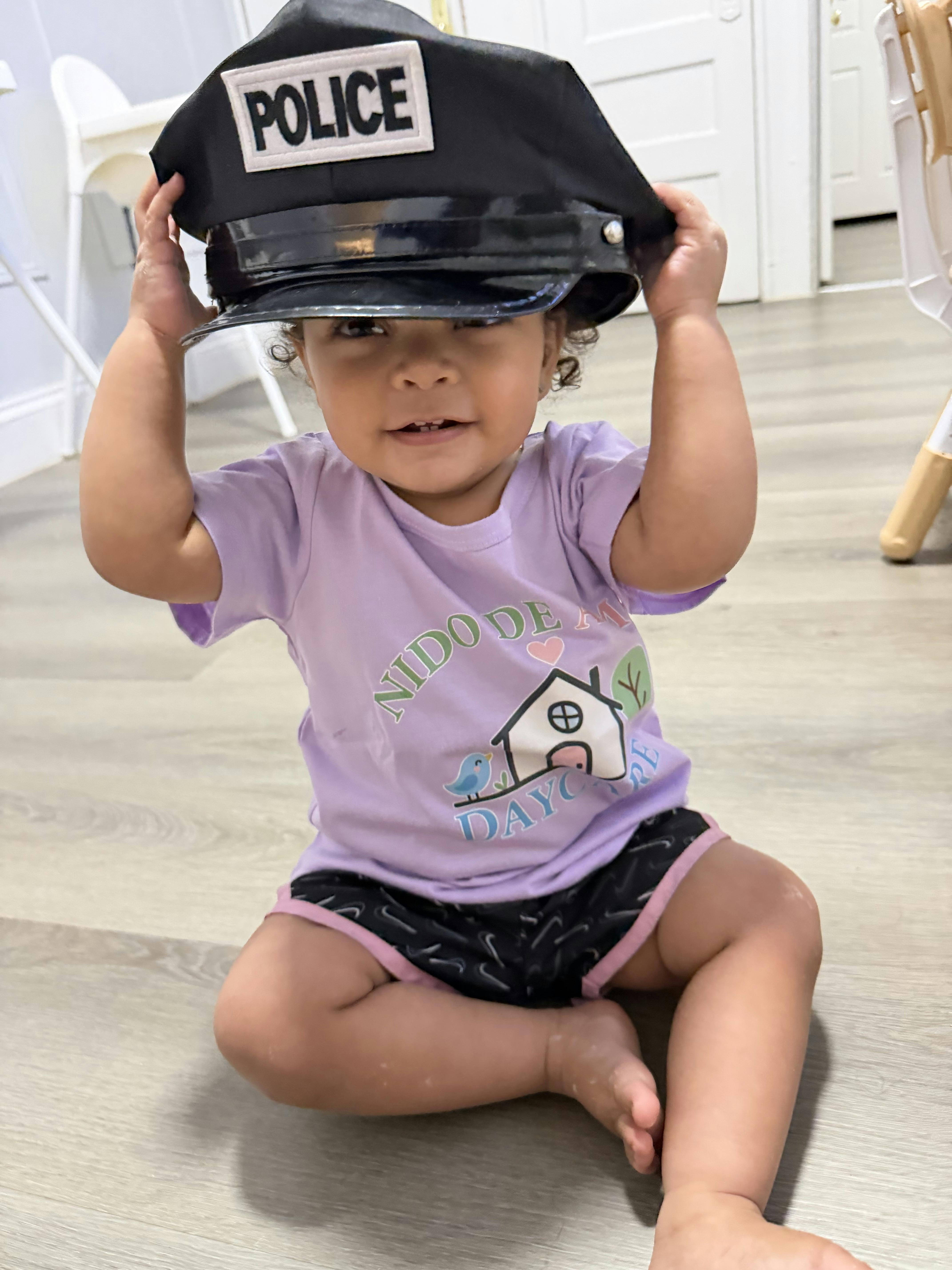 Child sitting on the floor wearing a large police hat