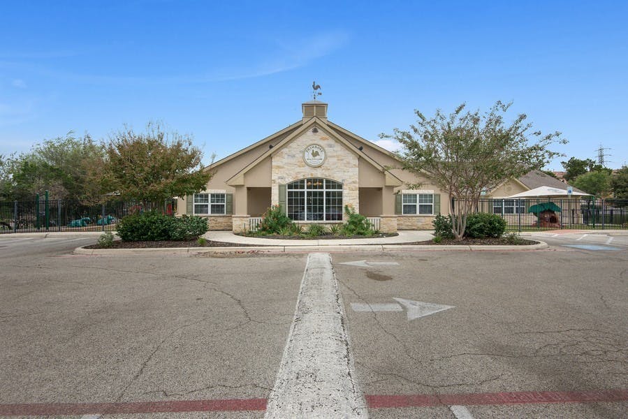Building with a stone facade and large windows, with a parking lot in front