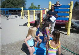 Children playing in a small pool with an adult nearby