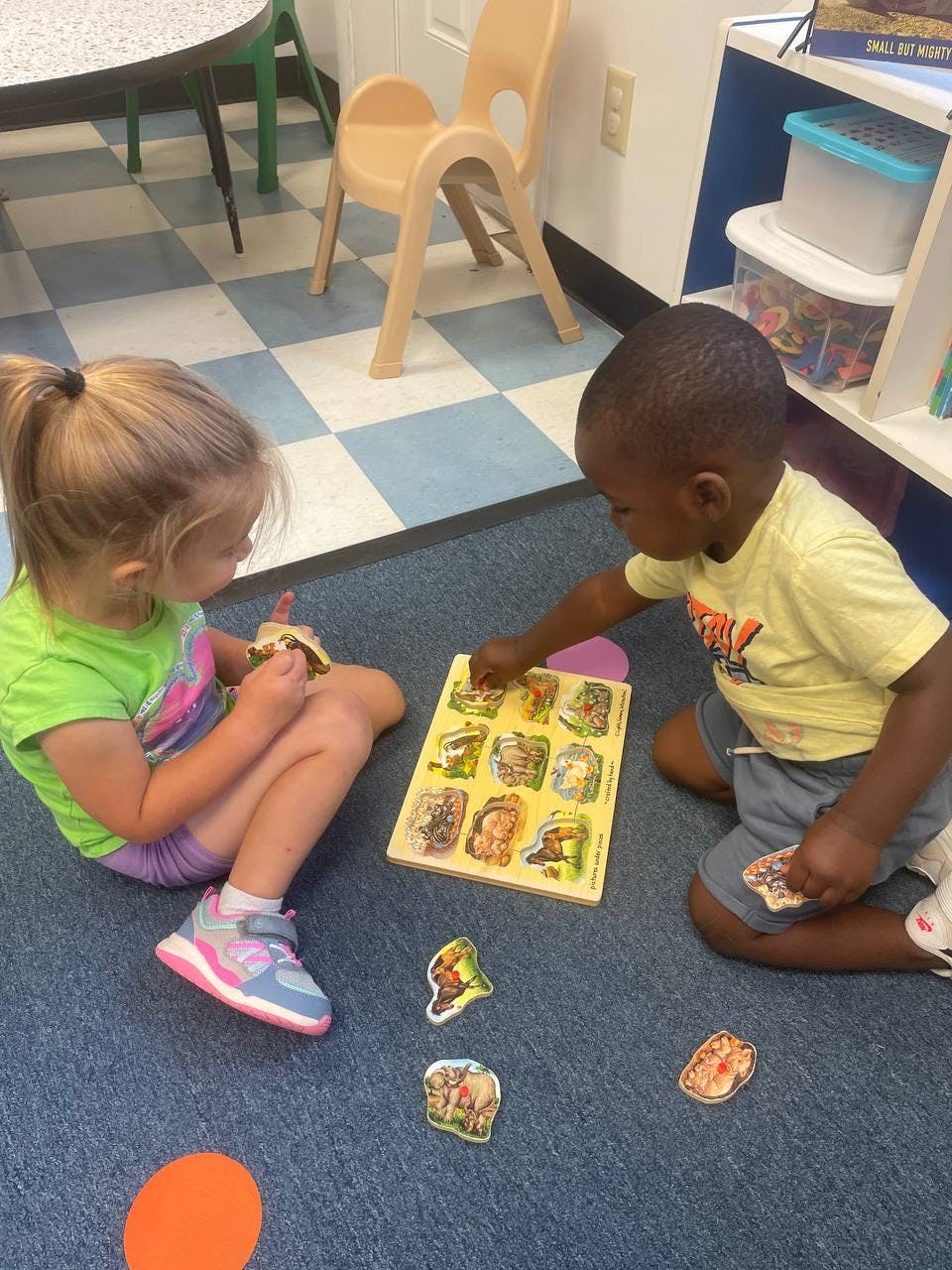 Two children playing with a puzzle on the floor