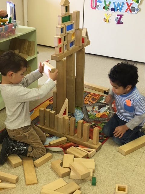 Two children playing with wooden blocks on the floor