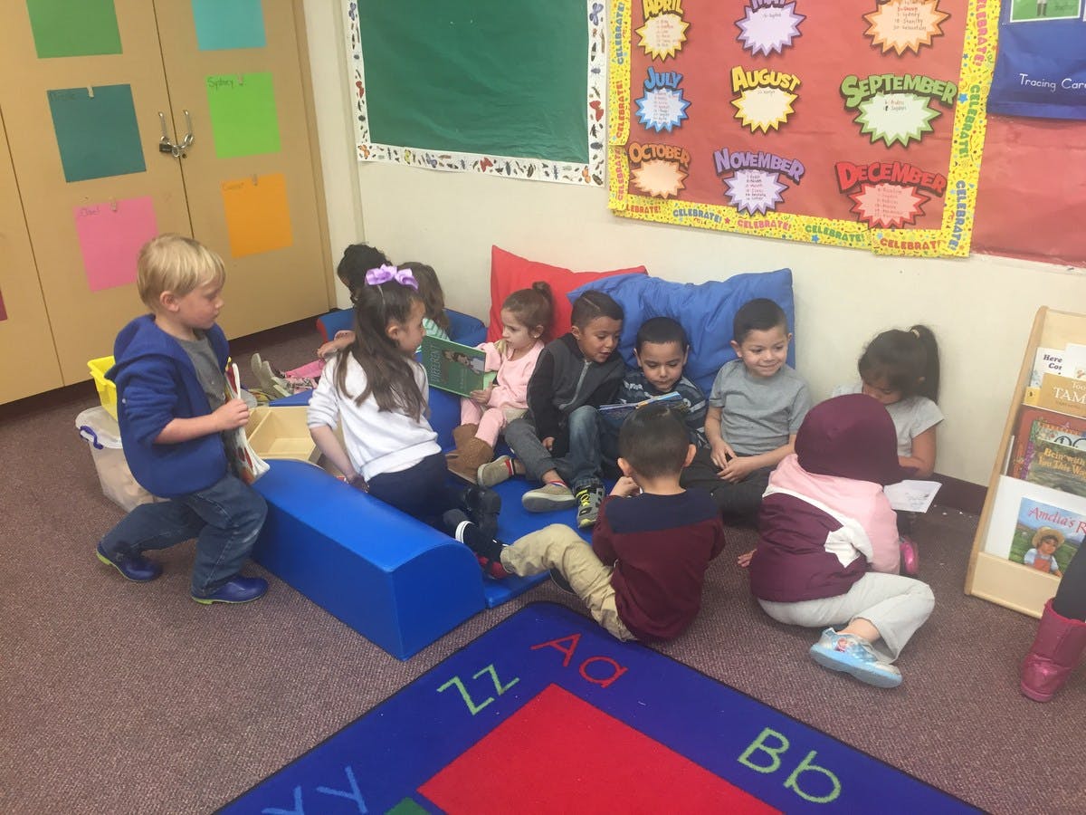 Children sitting on floor and cushions in a classroom