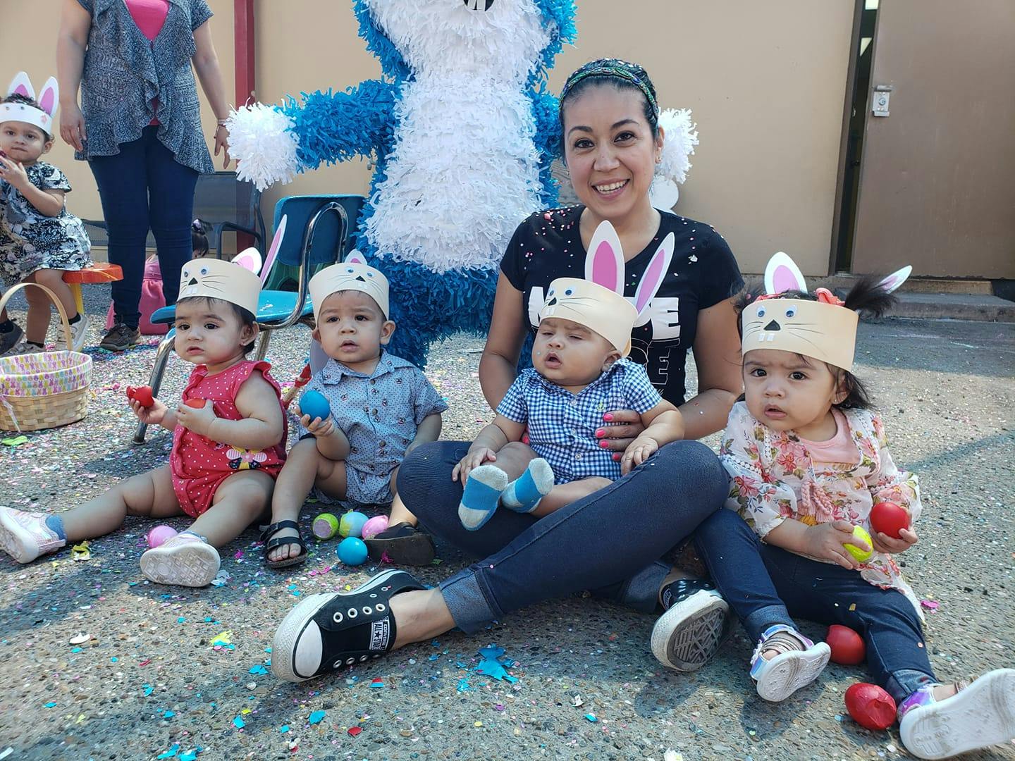 Person sitting on ground with four children wearing bunny ear headbands