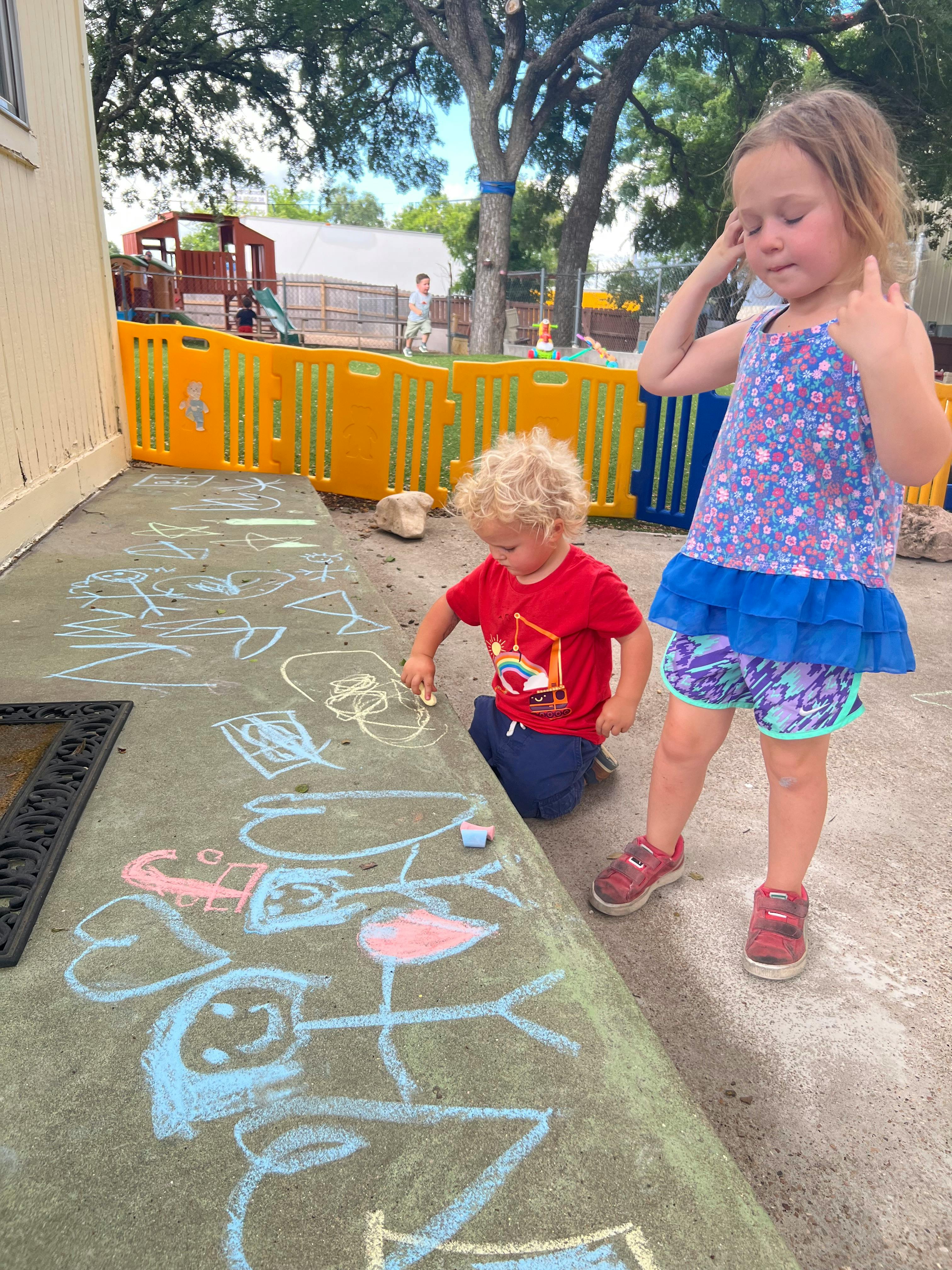 Two children drawing with chalk on a sidewalk
