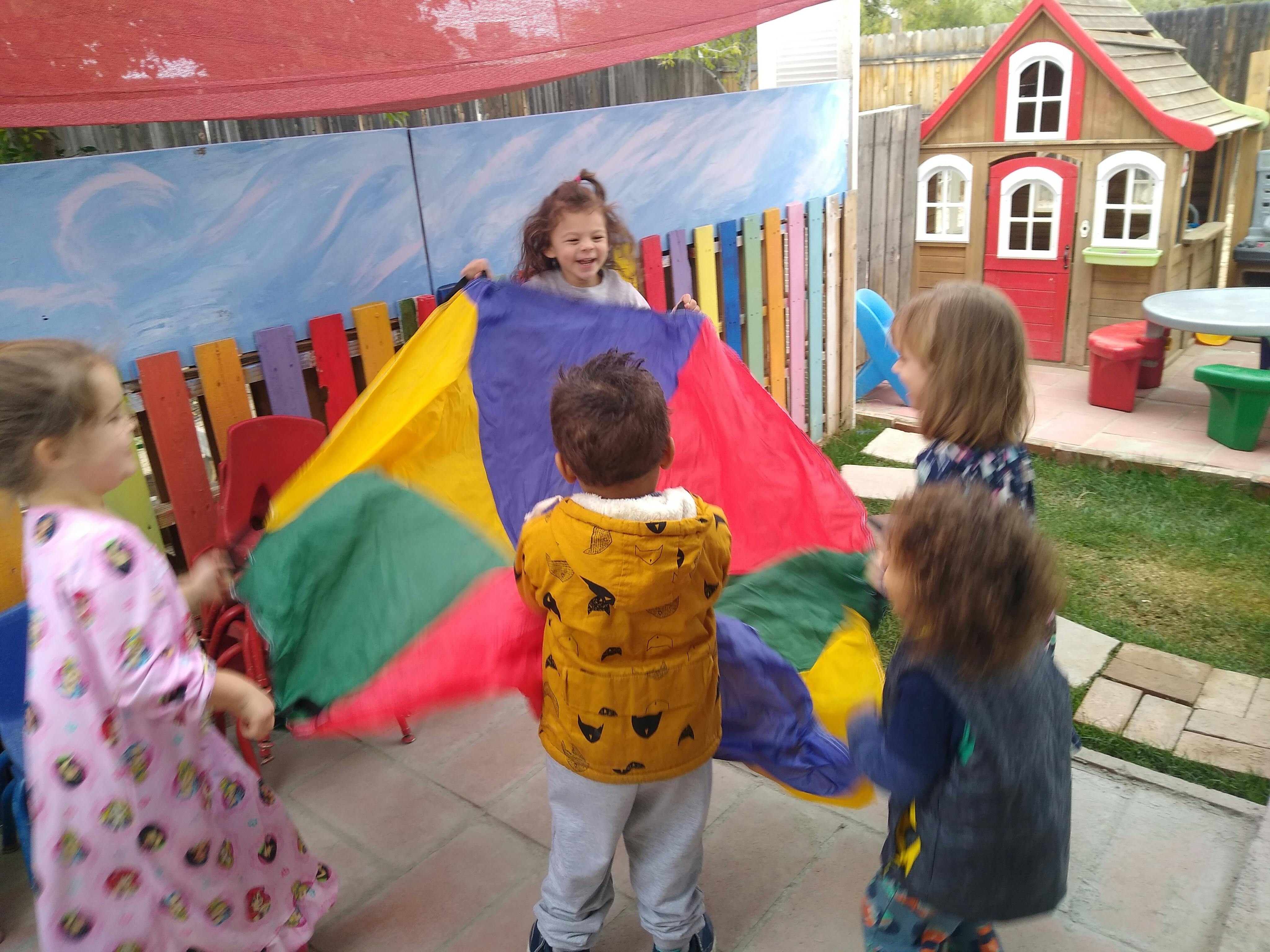 Children playing with a colorful parachute