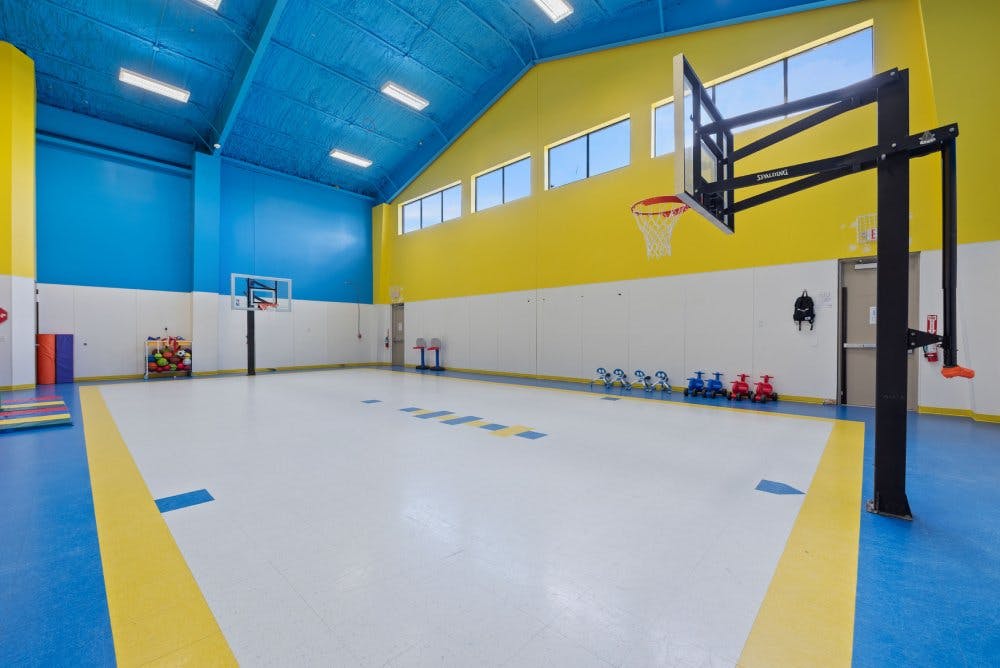Colorful indoor basketball court with two hoops and small ride-on toys