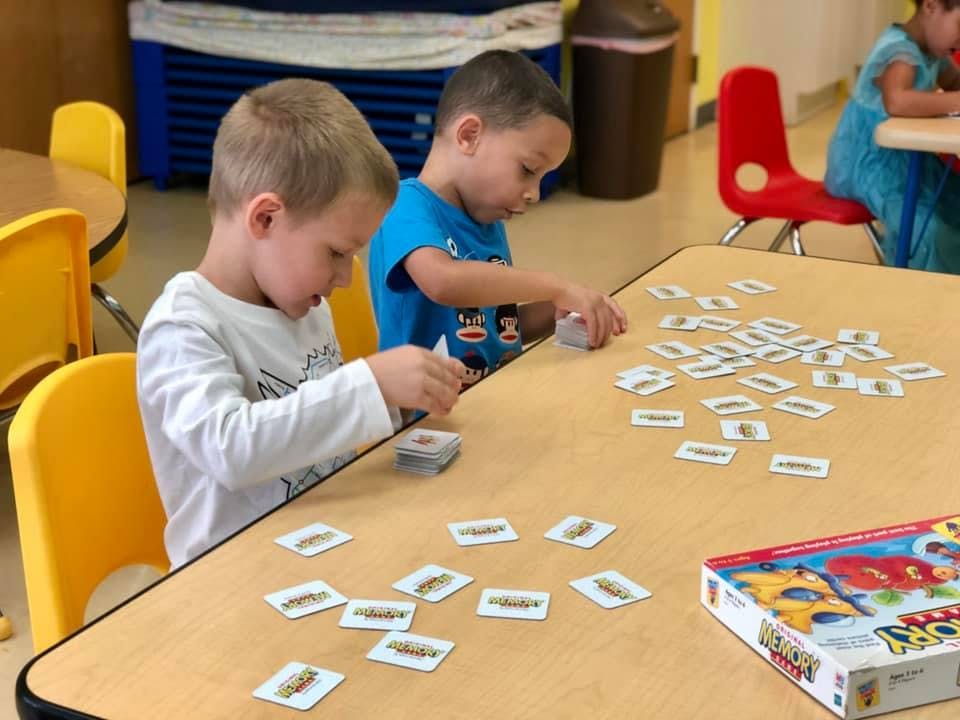Two children playing a card game at a table