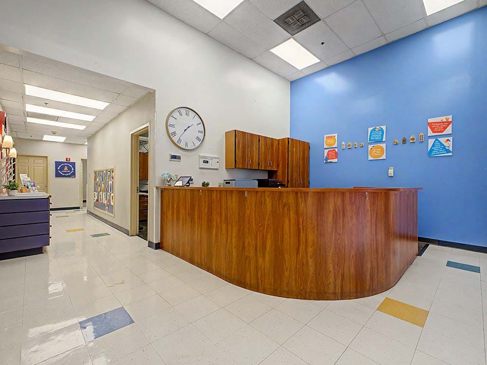 An empty reception area with a wooden desk and a blue wall with colorful signs