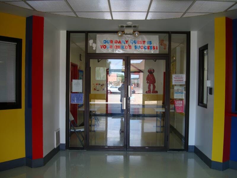 Glass double doors with a sign above reading "OUR DAILY QUEST IS KNOWLEDGE SUCCESS"