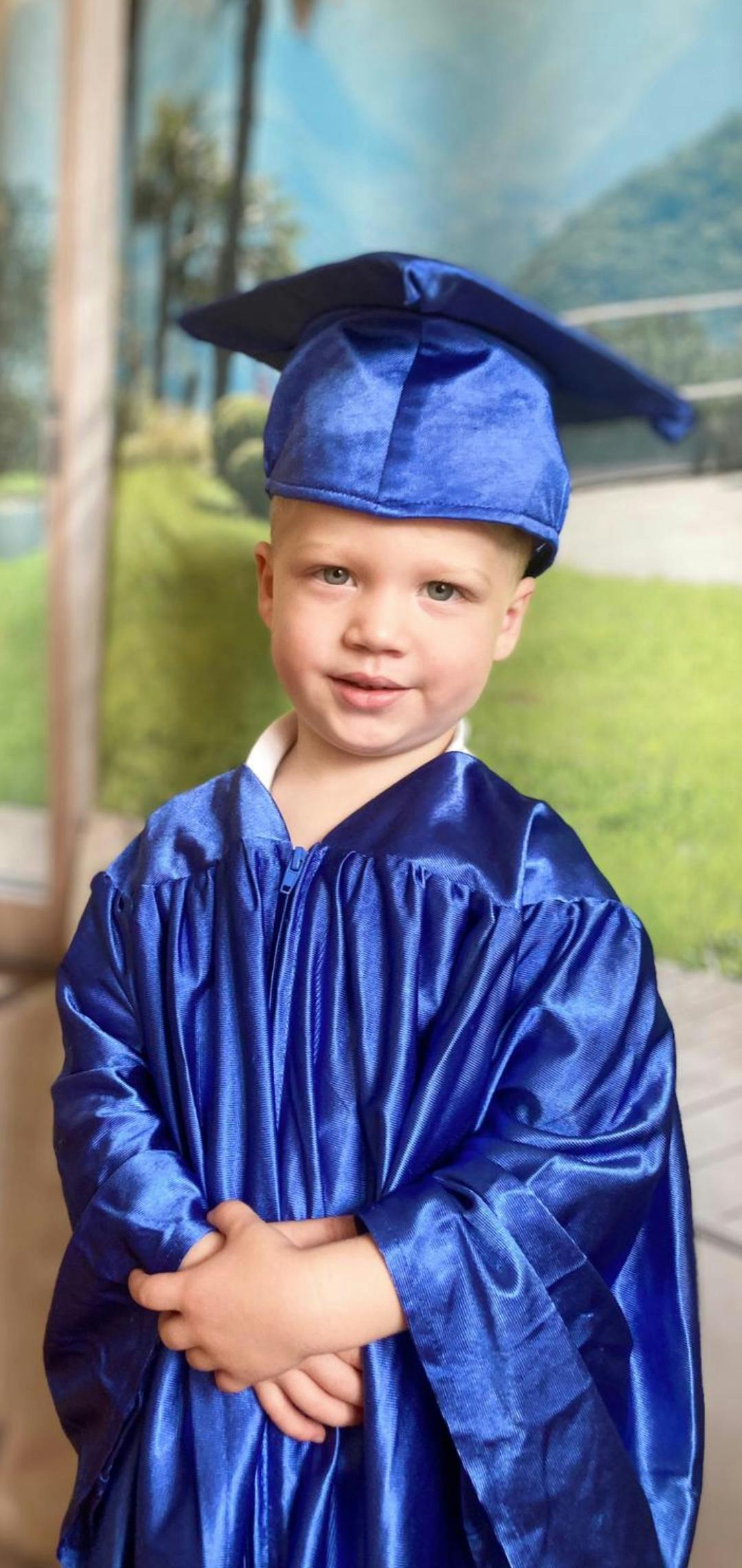 A young child wearing a blue graduation cap and gown