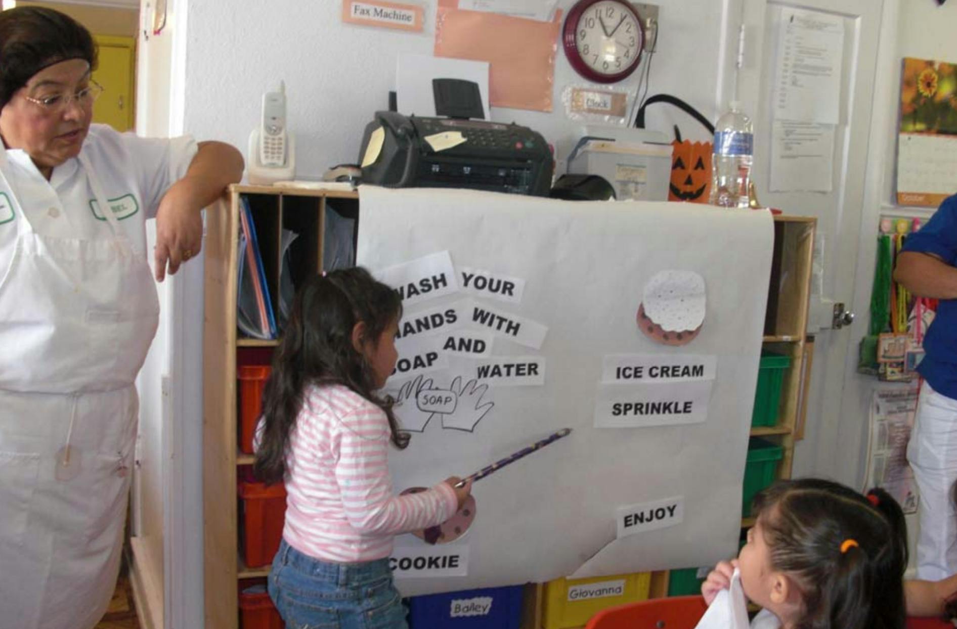 Adult and child looking at a sign that says "Wash your hands with soap and water"