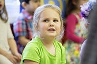 Child in a green shirt looking up with other children in the background