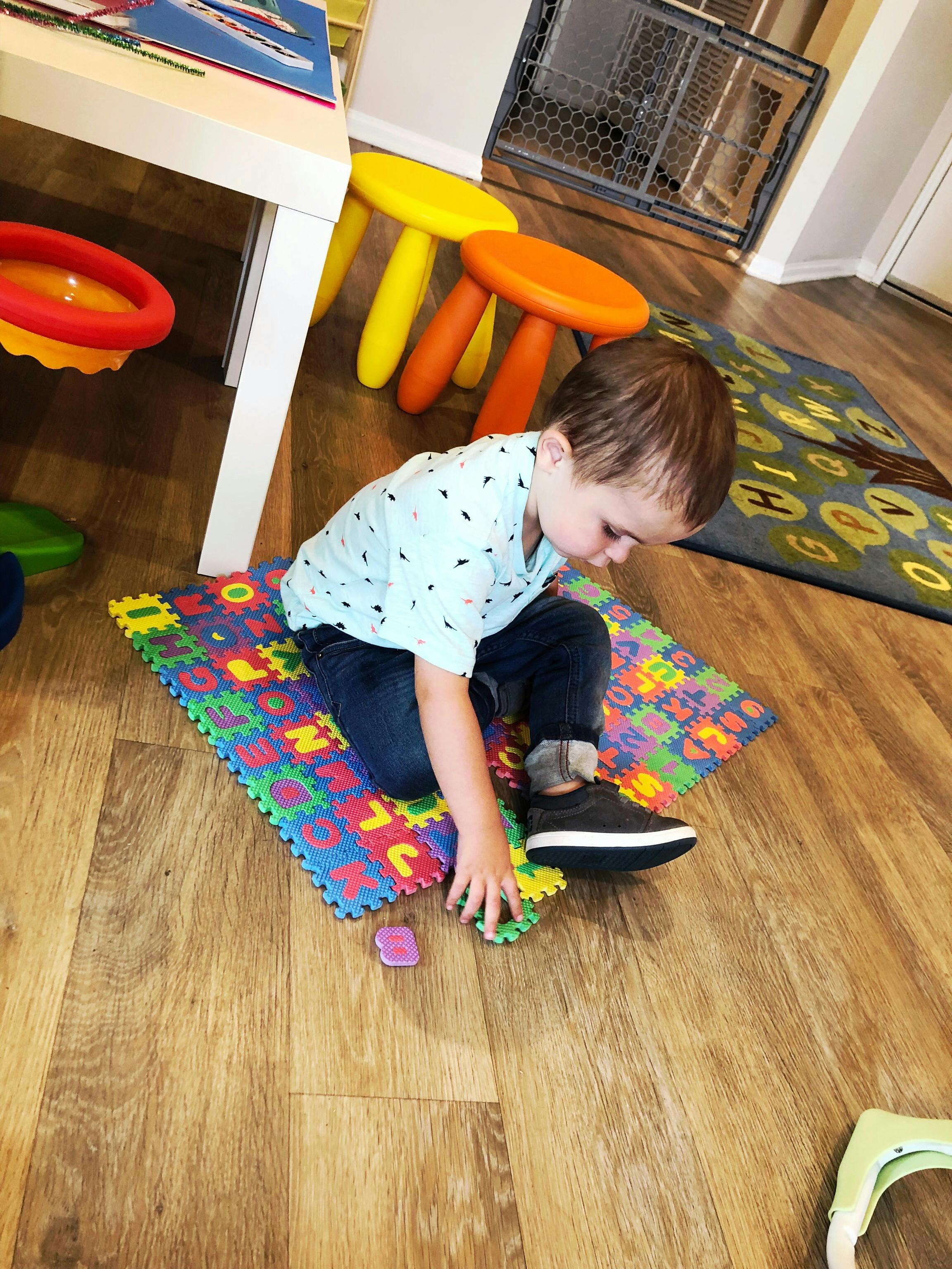 Child playing with alphabet puzzle mat on the floor