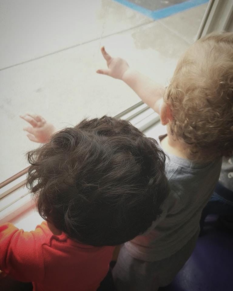 Two children looking out a window, one pointing