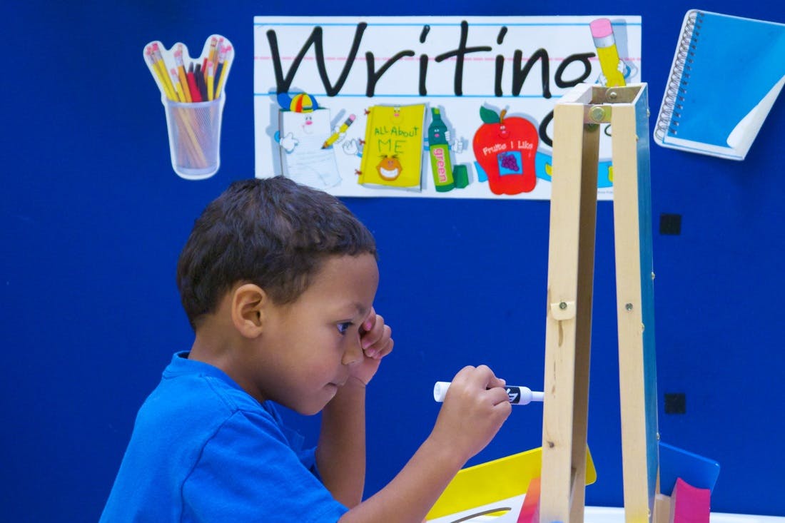 Child writing on an easel in a classroom