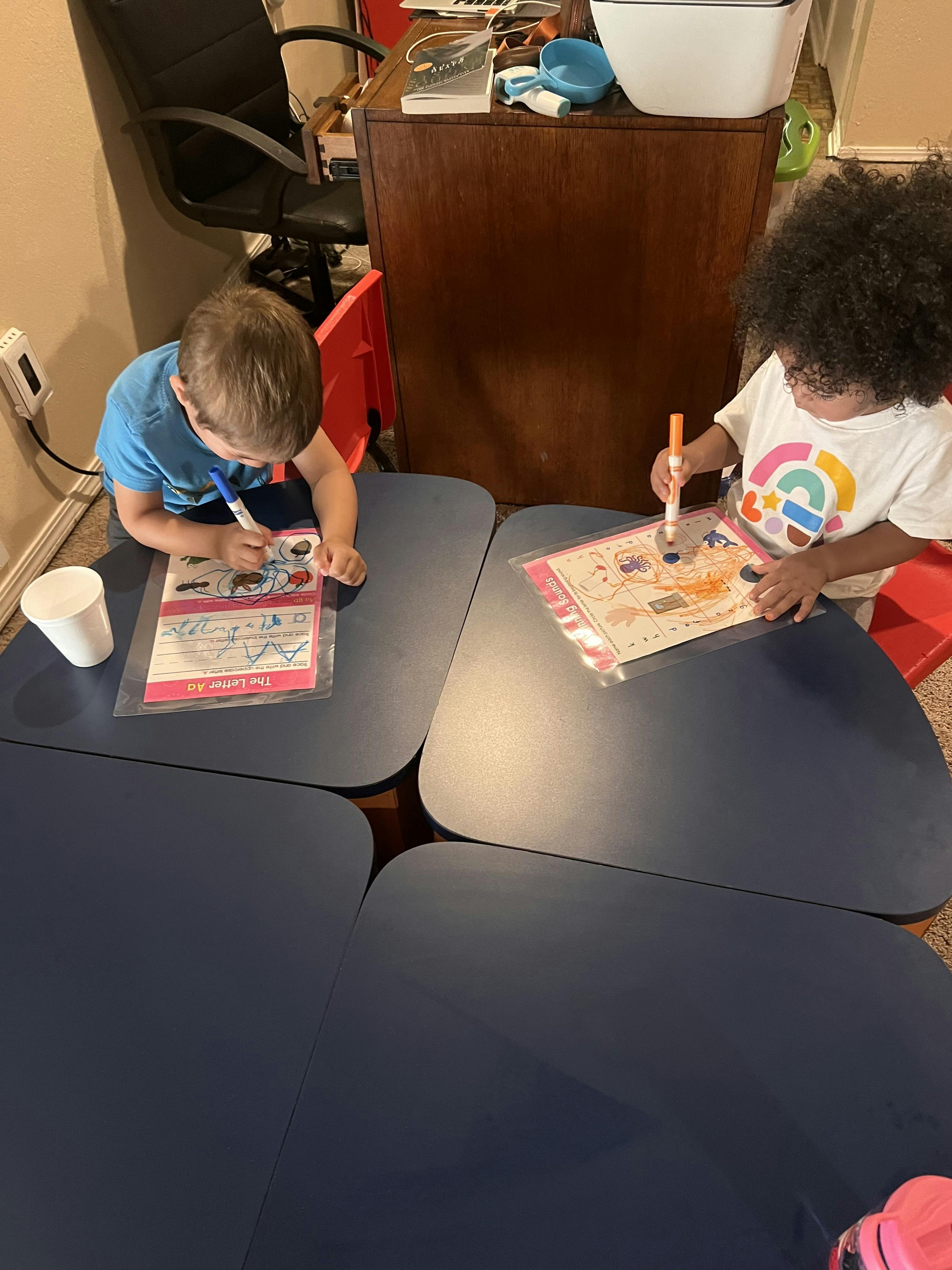 two children coloring on activity sheets at a table