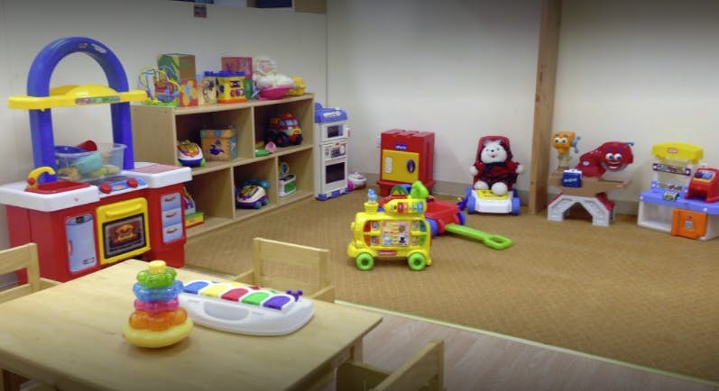 Playroom with various toys including a play kitchen, shelves, and floor toys