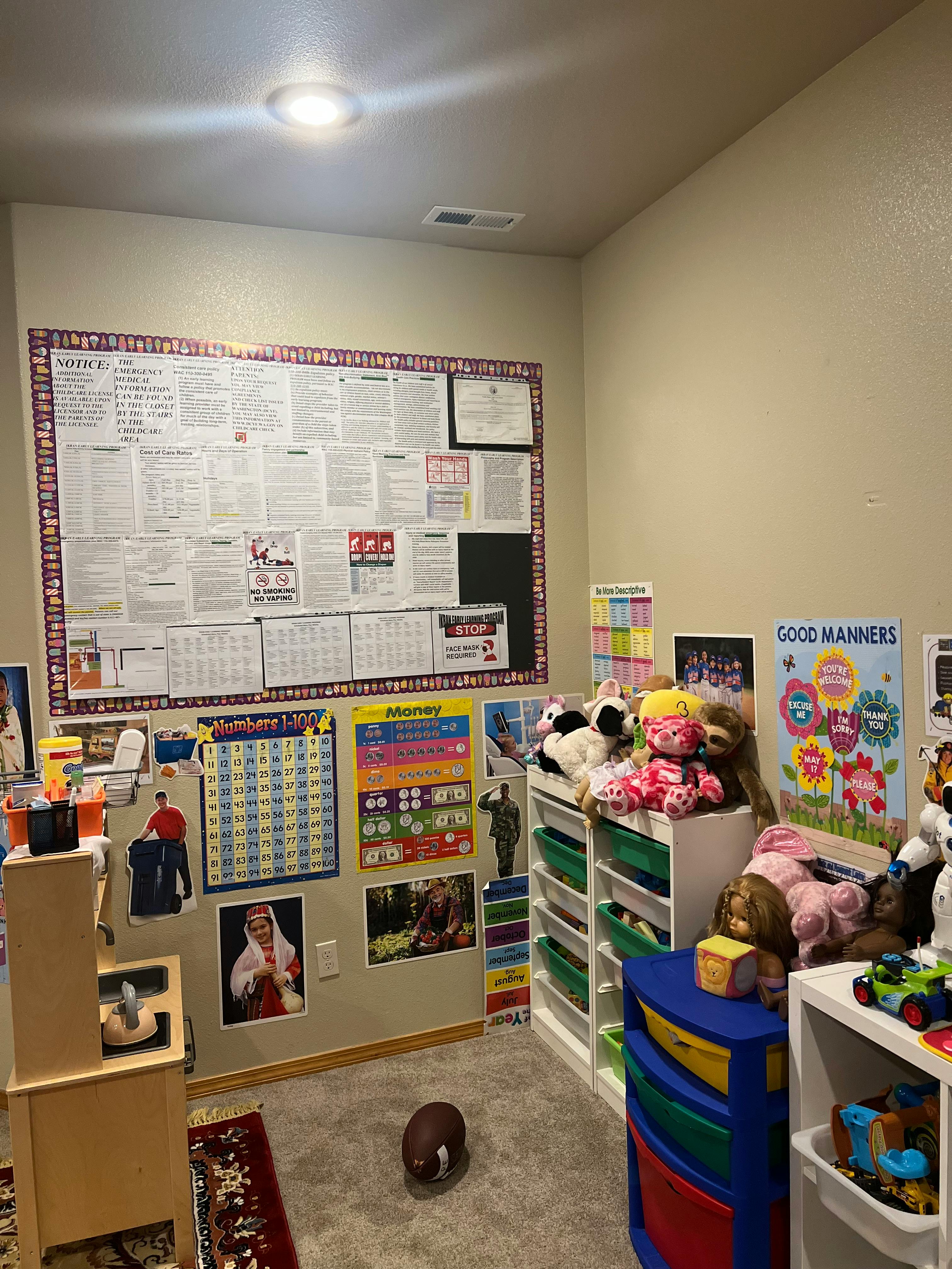 A room with a large bulletin board, posters, and shelves of toys