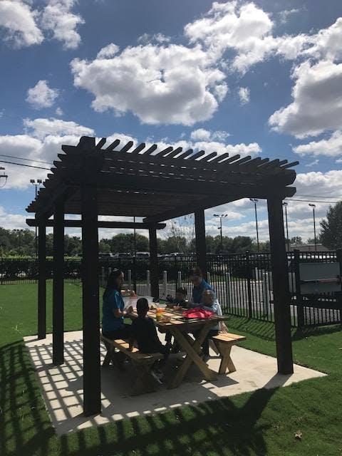 People sitting at a picnic table under a pergola