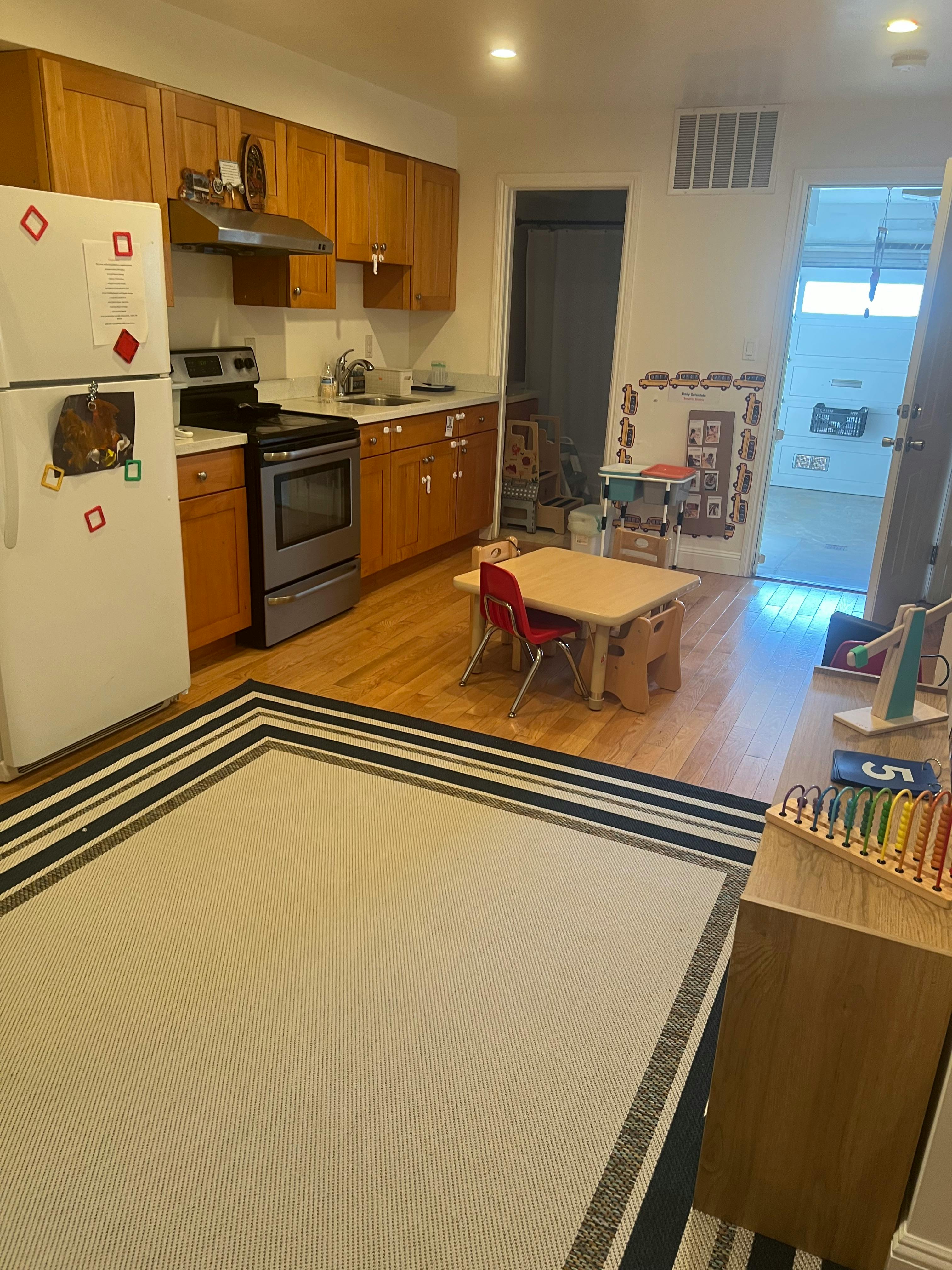 Kitchen with wooden cabinets, white refrigerator, and small table with red chairs