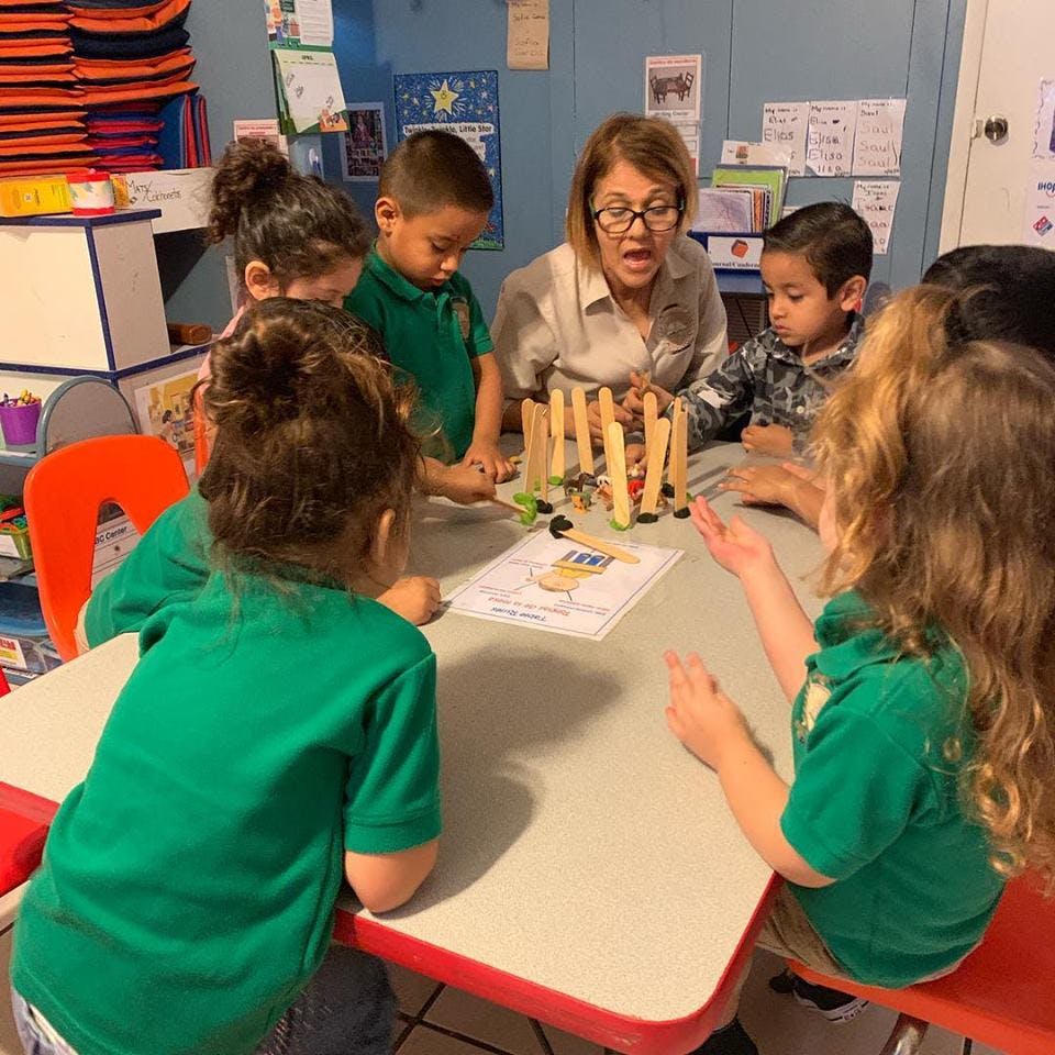 Adult and children gathered around a table with craft sticks